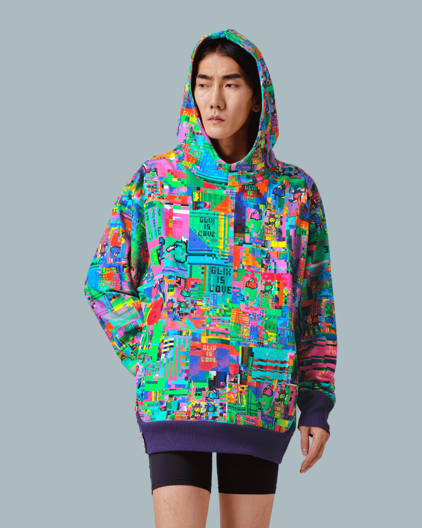 A male model wearing GLIX IS LOVE hoodie with glitch textures printed on the front side and wearing short tights