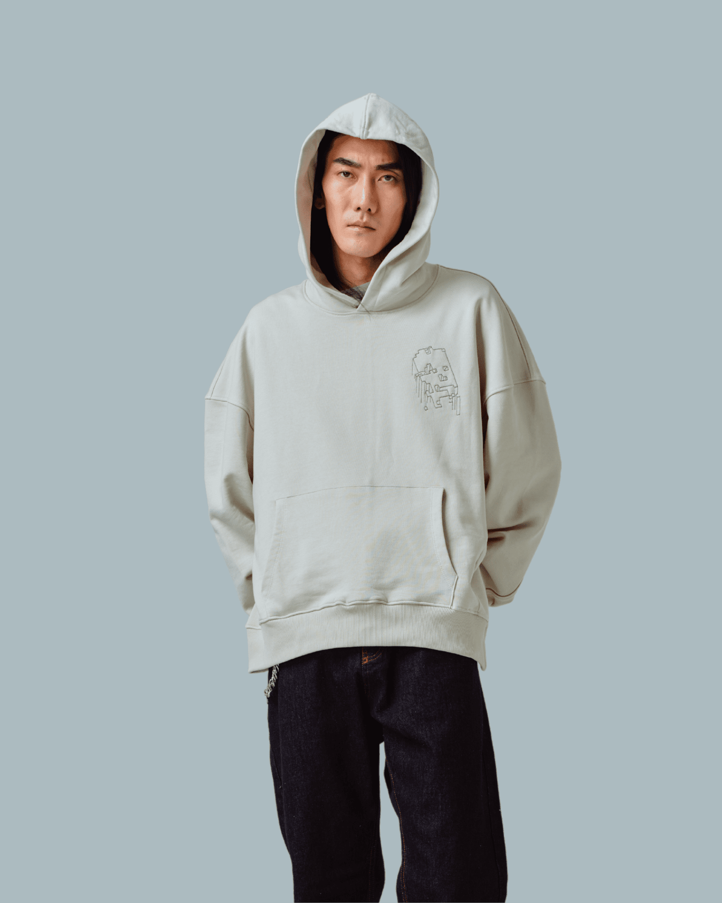 A male model wearing Grey Matter Hoodie with glitchy skull printed on the front side and wearing a pair of jeans