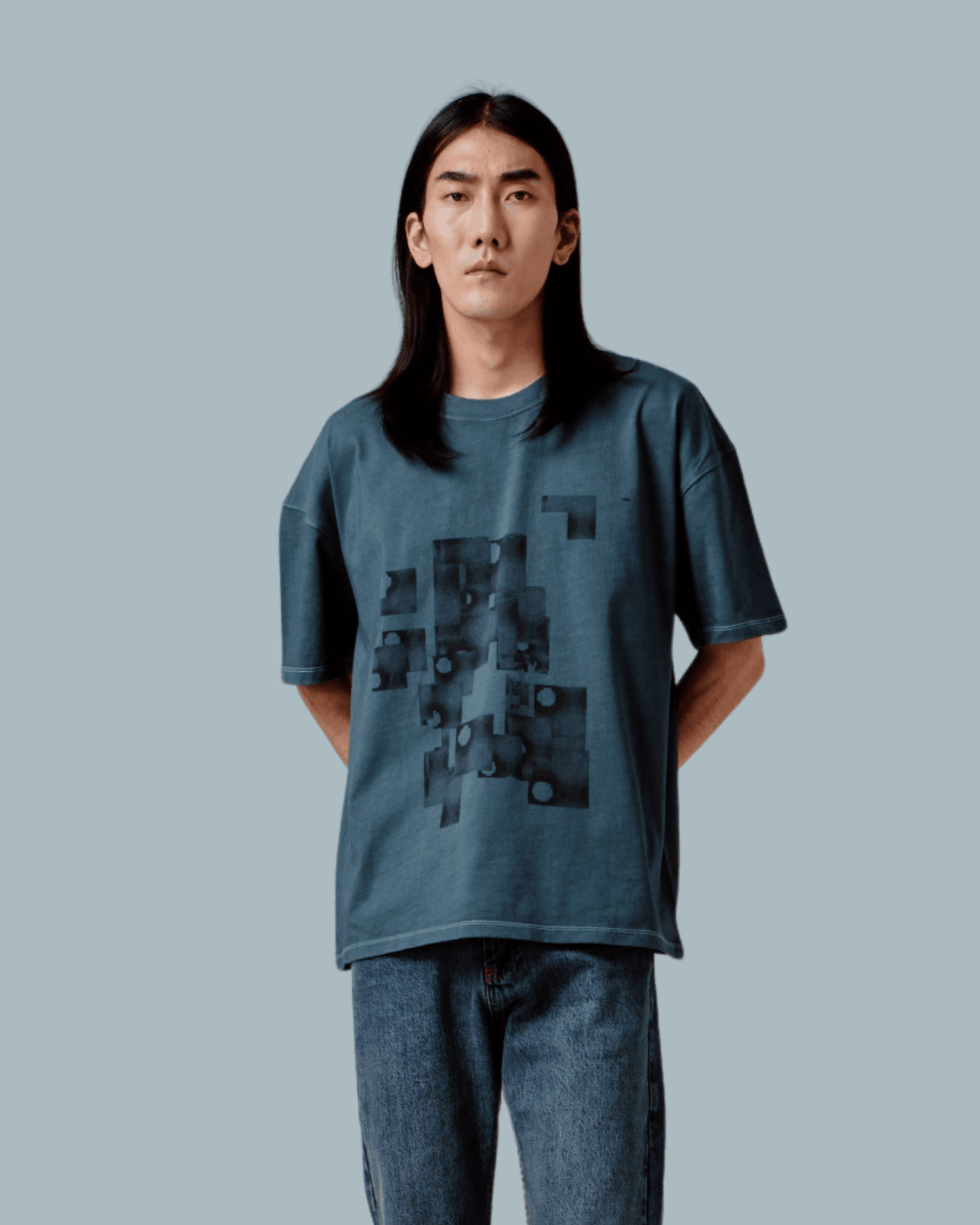 A male model wearing a gray oversized T-shirt with GLIX pattern embroidered, glitch textures printed on front side.