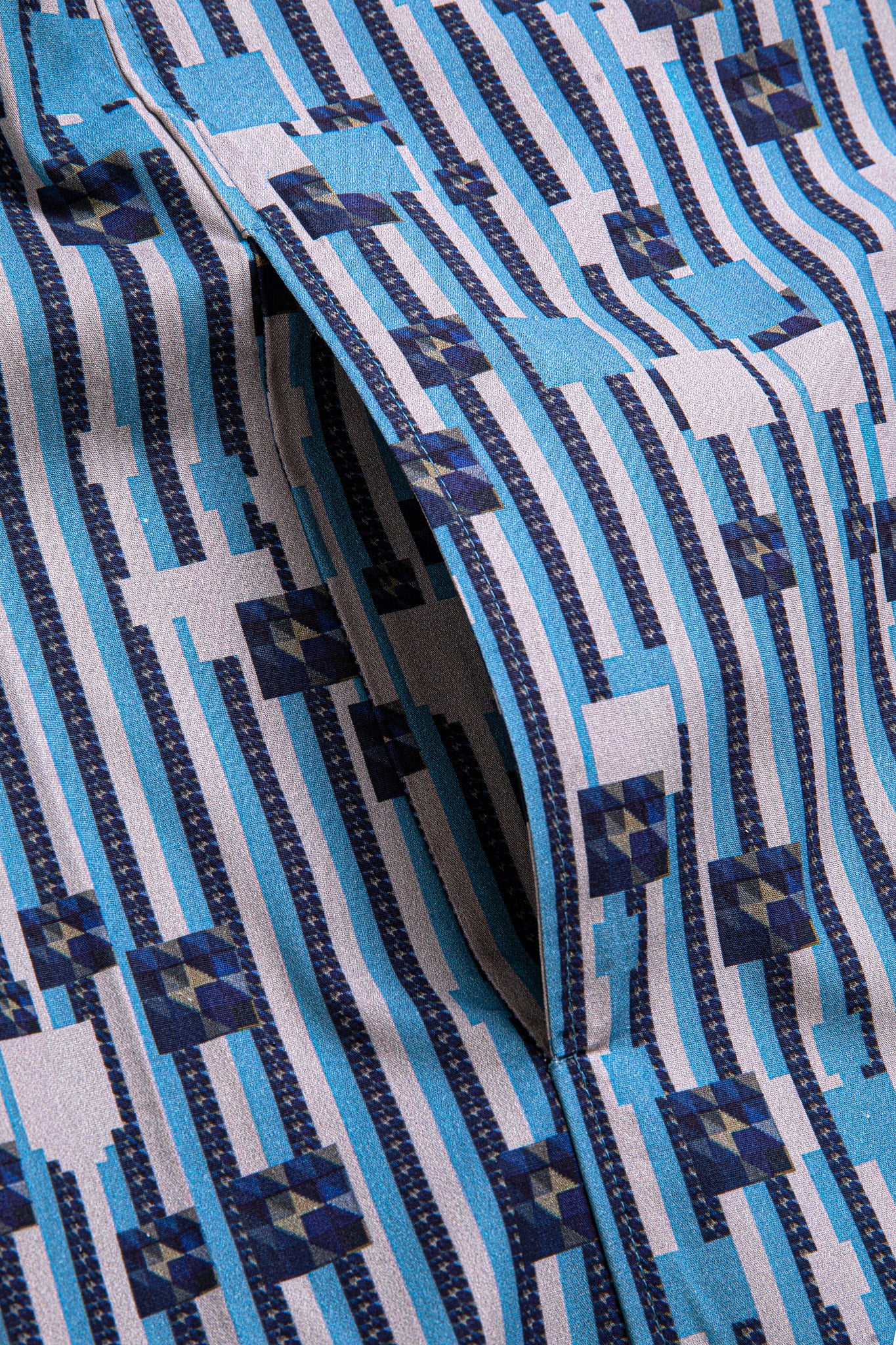 Macro close-up of the side pocket on the GLIX "Water Crackle" shirt, showcasing the blue and white vertical stripe pattern integrated with dark blue and grey pixelated geometric floral graphics.