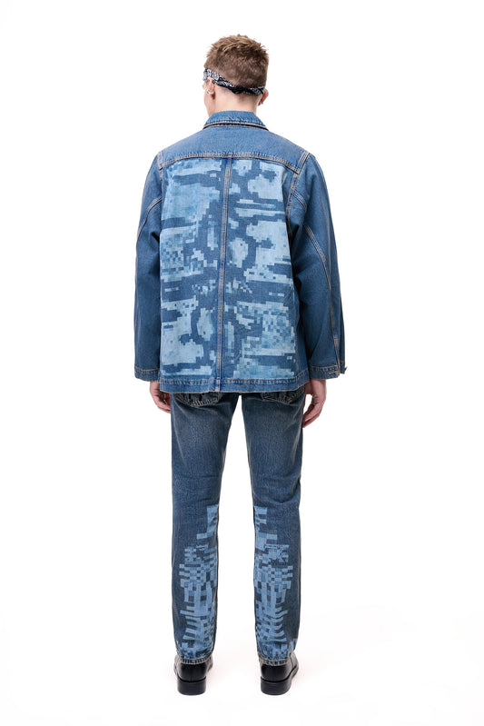 Rear view of a male model wearing the GLIX "Coral Biome" oversized denim jacket, featuring a large light blue pixelated digital glitch print across the back, styled with matching pixel-print jeans and black boots.