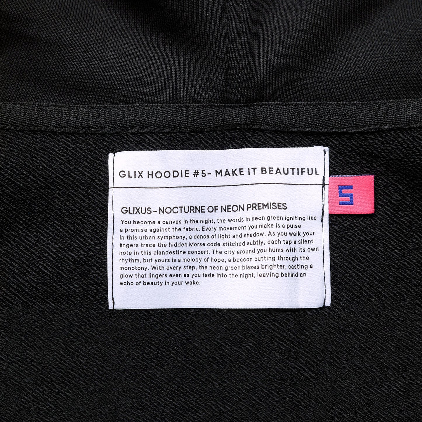 Close-up of the interior neck label for GLIX HOODIE #5 - MAKE IT BEAUTIFUL, featuring the "GLIXUS - NOCTURNE OF NEON PREMISES" brand manifesto