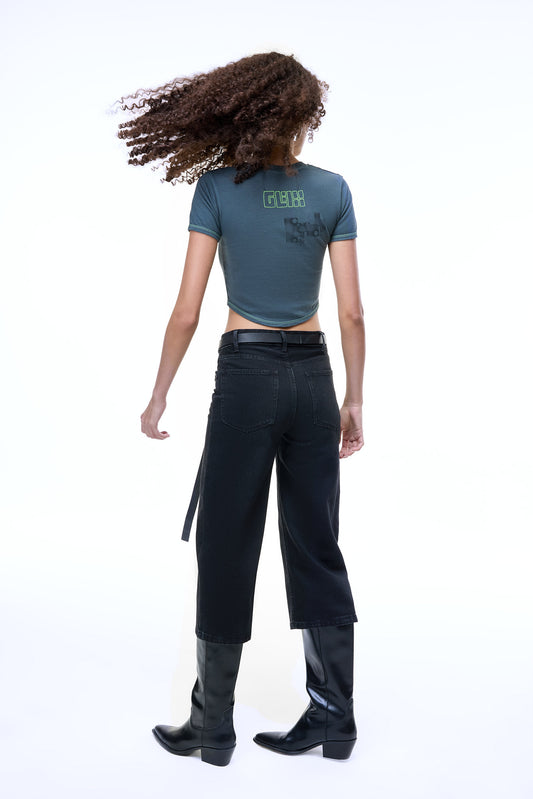 Back view of a model wearing the GLIX MOLD PROBLEM dark grey crop top baby tee with a green neon logo and black glitch graphic.