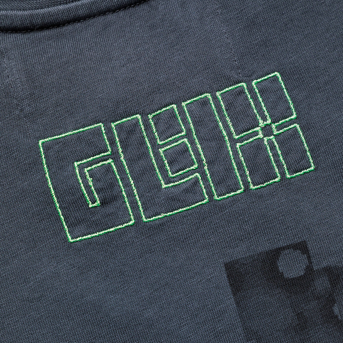 Zoomed in detail of a white GLIX baby tee showing the high-density heavyweight cotton texture and precision-stitched logo.