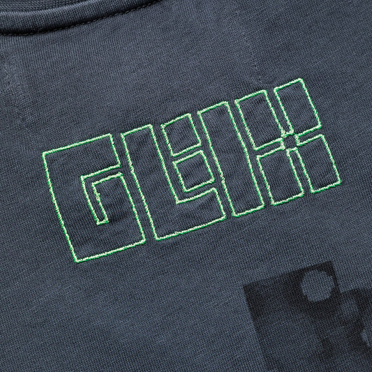 Zoomed in detail of a white GLIX baby tee showing the high-density heavyweight cotton texture and precision-stitched logo.