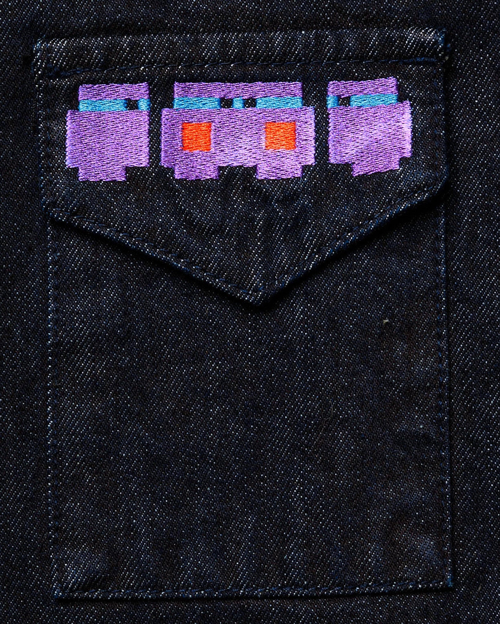 Embroidered pixelated characters on a denim pocket