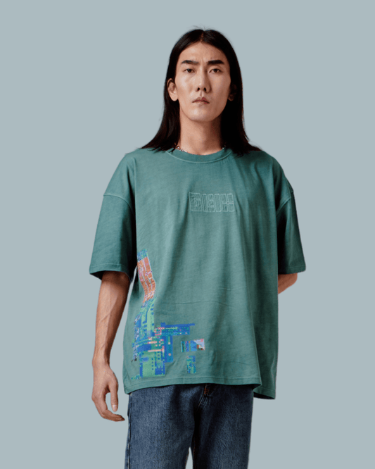 A male model wearing a green oversized T-shirt with GLIX logo embroidered, glitch textures printed on front side.