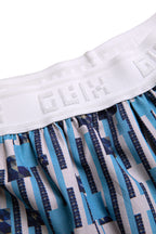 Close-up lifestyle view of the GLIX "Water Crackle" boxing shorts on a model, highlighting the wide white elastic waistband with the tonal embroidered GLIX logo and the blue and white pixelated floral stripe pattern.