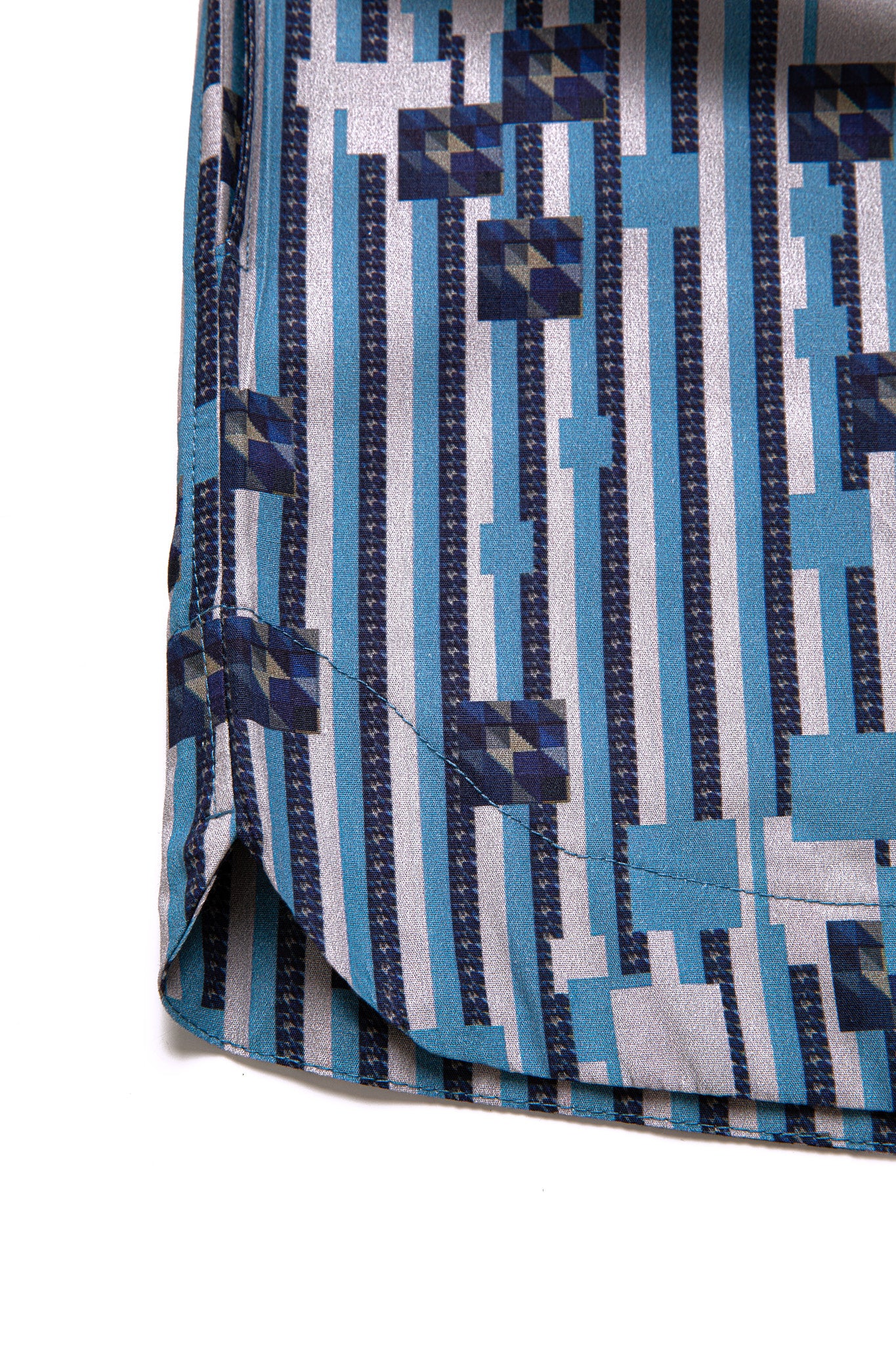 Macro close-up of the curved bottom hem and side slit on the GLIX "Water Crackle" boxing shorts, highlighting the blue and white vertical stripe pattern and pixelated geometric floral print.