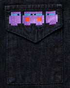 Macro close-up of the large "Totem" back graphic on dark wash denim, featuring high-density pixelated embroidery in vibrant purple, orange, and blue threads.