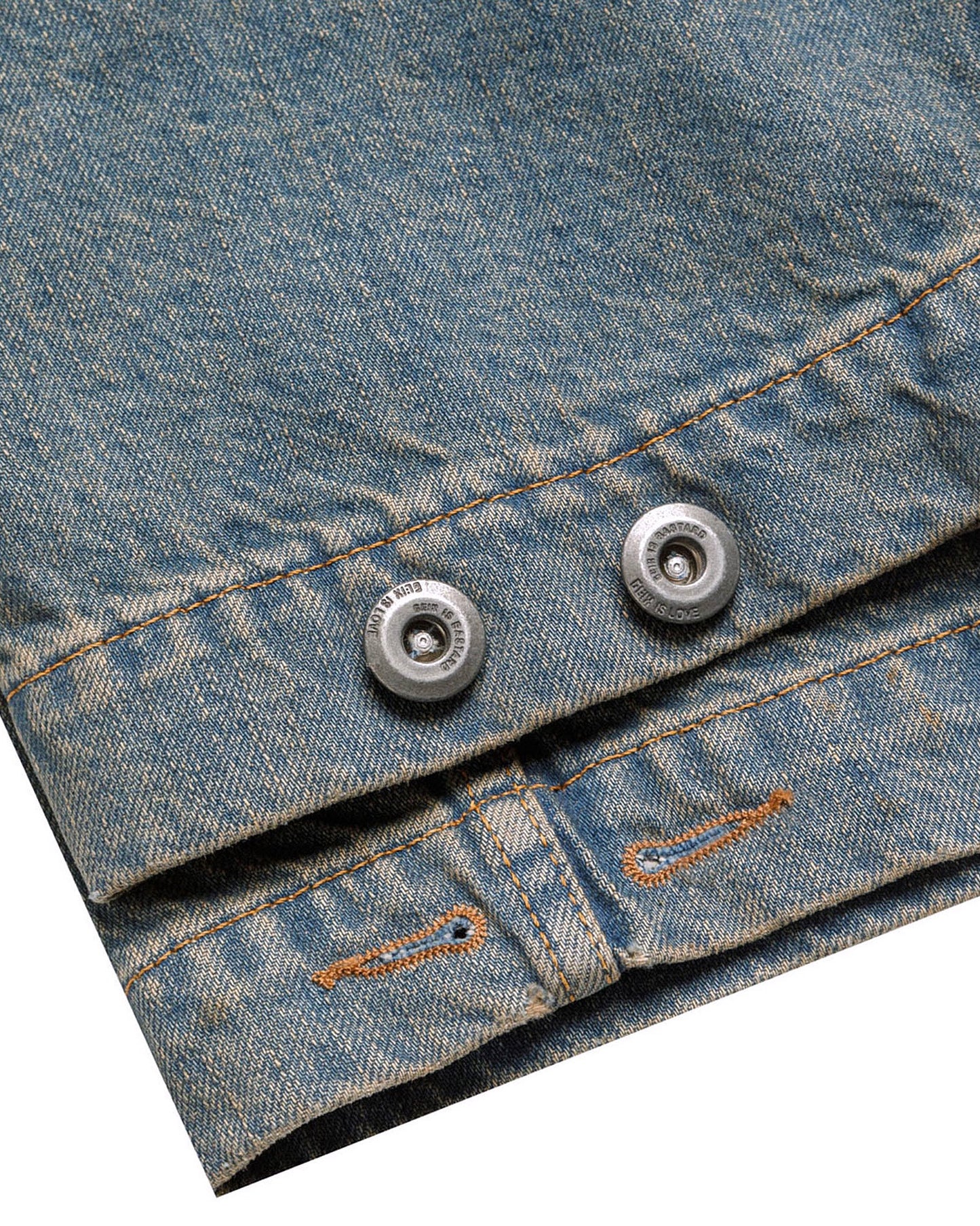 Macro close-up of the GLIX "Coral Biome" denim jacket cuff, showing silver-toned metal snap buttons engraved with "GLIX IS LOVE" and "GLIX IS BASTARD" alongside premium contrast orange stitching on blue denim.