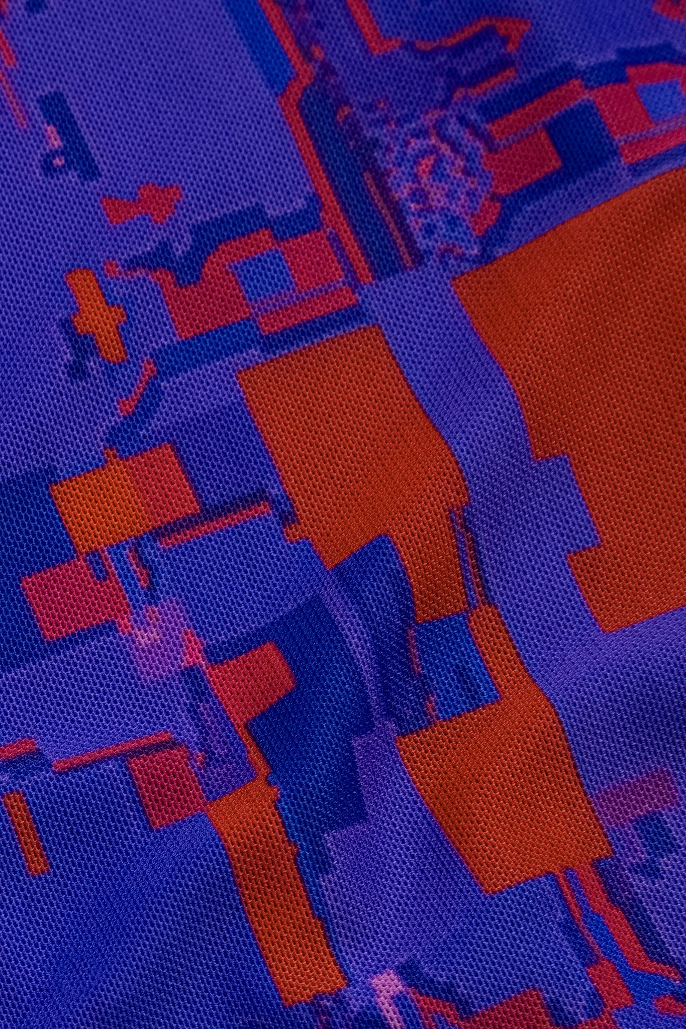 Macro close-up of the white rectangular GLIX logo patch on the back of the "#404.Blush" glitch dress, set against the purple mesh fabric with red and orange pixelated patterns.