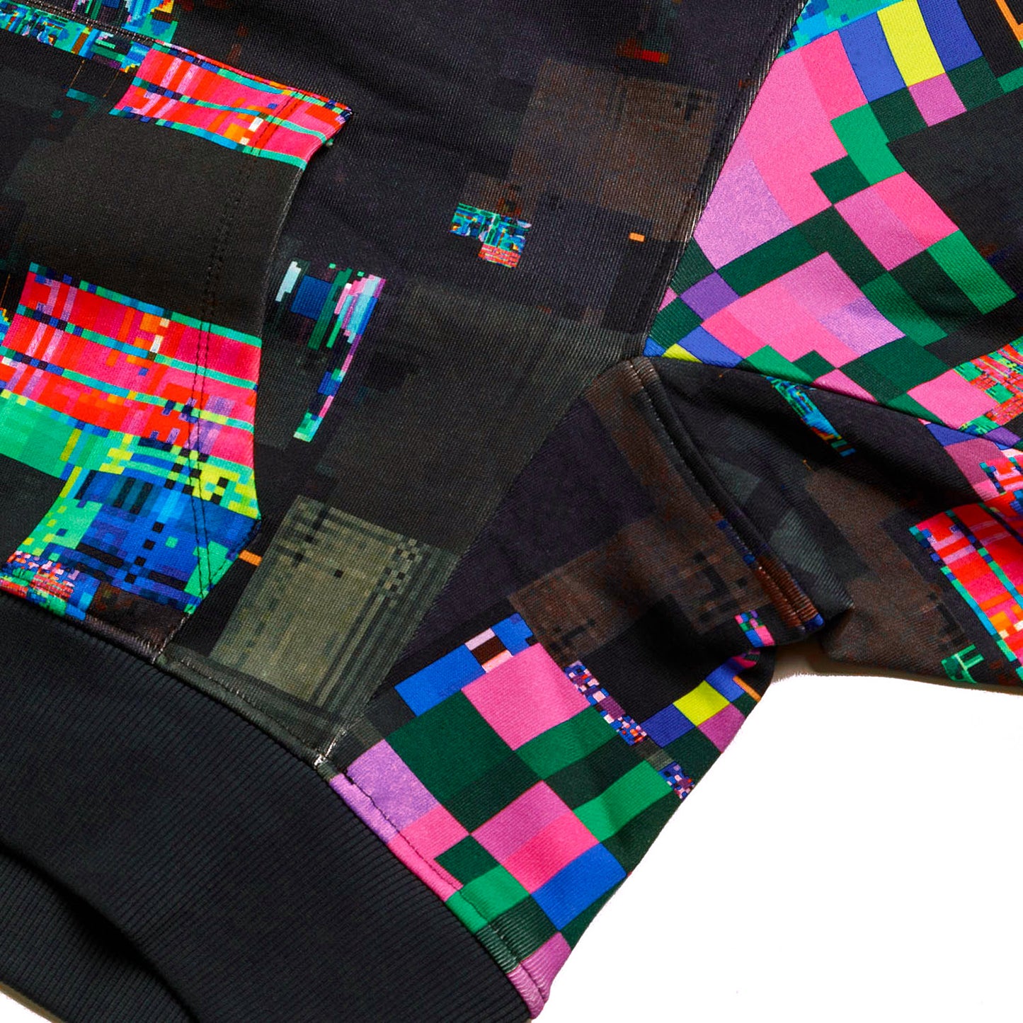 Detailed view of the GLIX "Screen Error" hoodie showing the side seam and sleeve attachment, featuring an all-over digital glitch print with vibrant pink, green, and blue pixel blocks against a dark textured background.