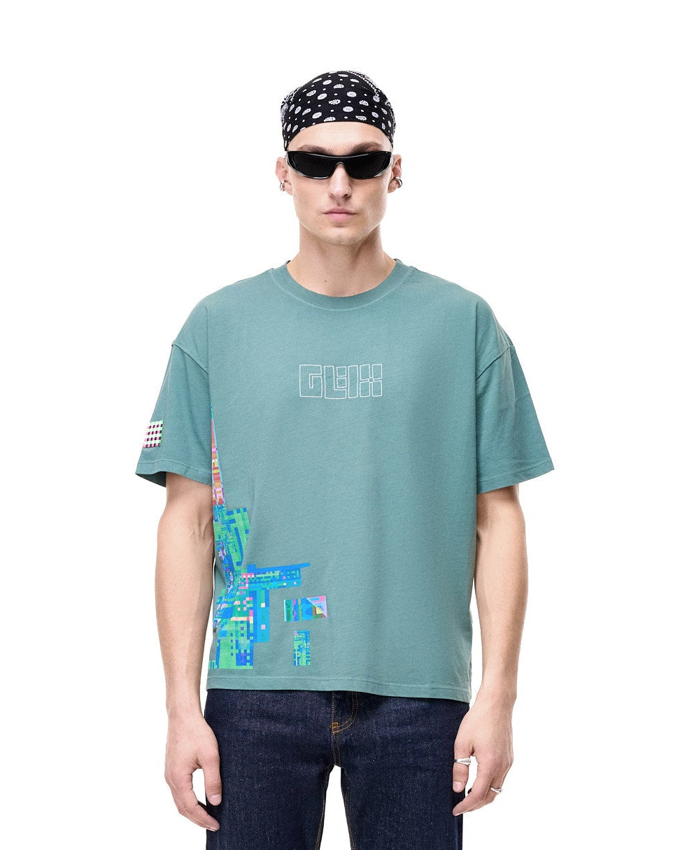 Person wearing a teal t-shirt with graphic design and dark jeans on a white background