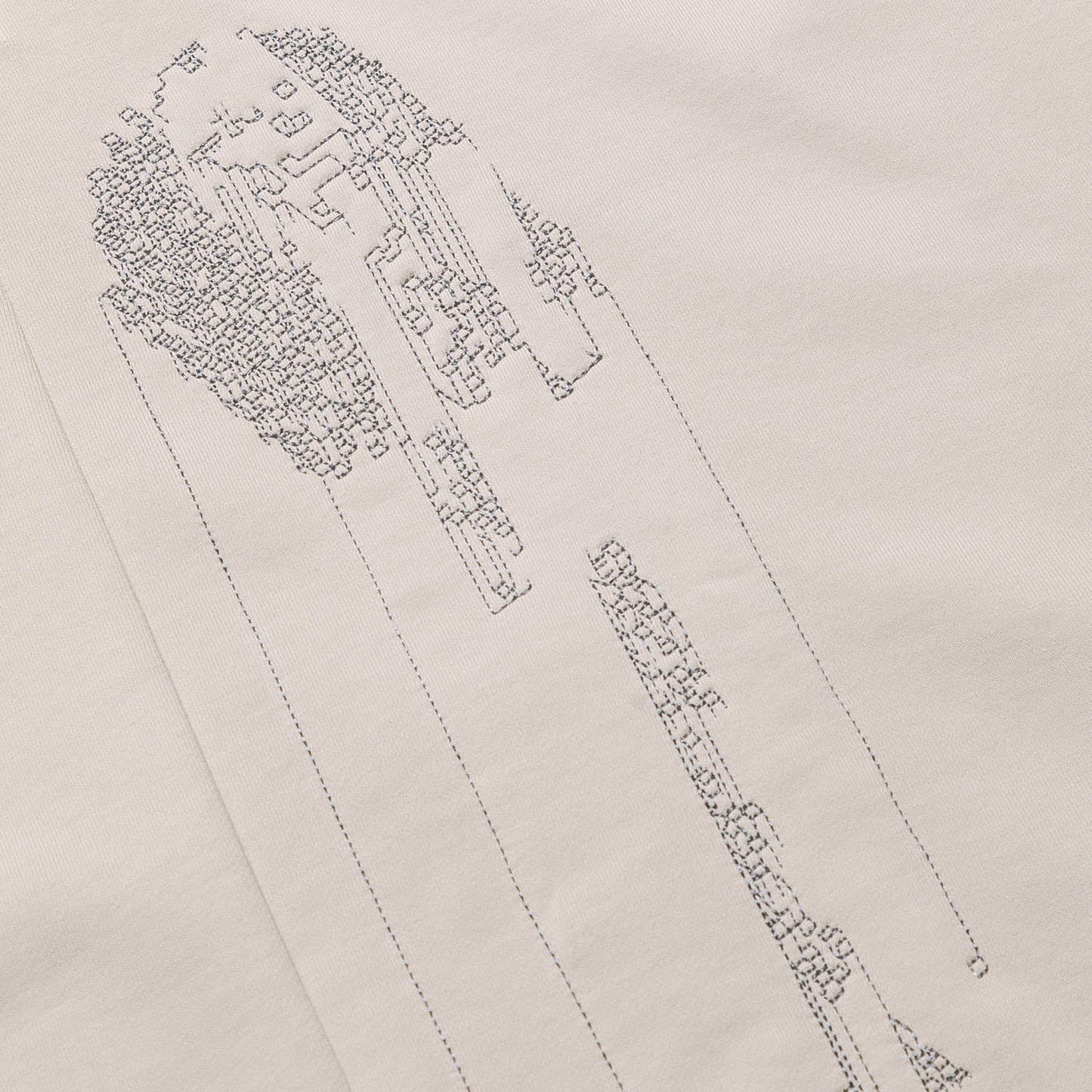 Extreme close-up of the light grey GLIX "Grey Matter" hoodie, highlighting the intricate grey tonal stitching of the vertical digital glitch embroidery.