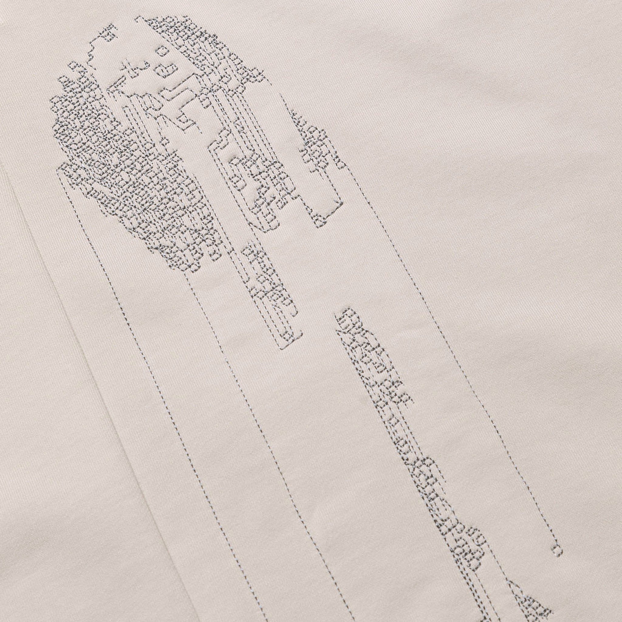 Extreme close-up of the light grey GLIX "Grey Matter" hoodie, highlighting the intricate grey tonal stitching of the vertical digital glitch embroidery.