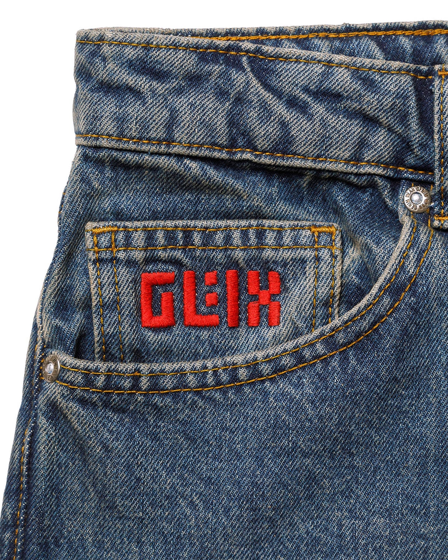 Macro close-up of the front coin pocket on the GLIX "Jetpack" feminine fit jeans, featuring a red embroidered GLIX logo on mid-wash denim with contrast orange stitching.
