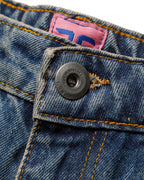 Macro close-up of the front closure on the GLIX "Jetpack" masculine fit jeans, featuring a silver branded button embossed with "GLIX IS BASTARD / GLIX IS LOVE"