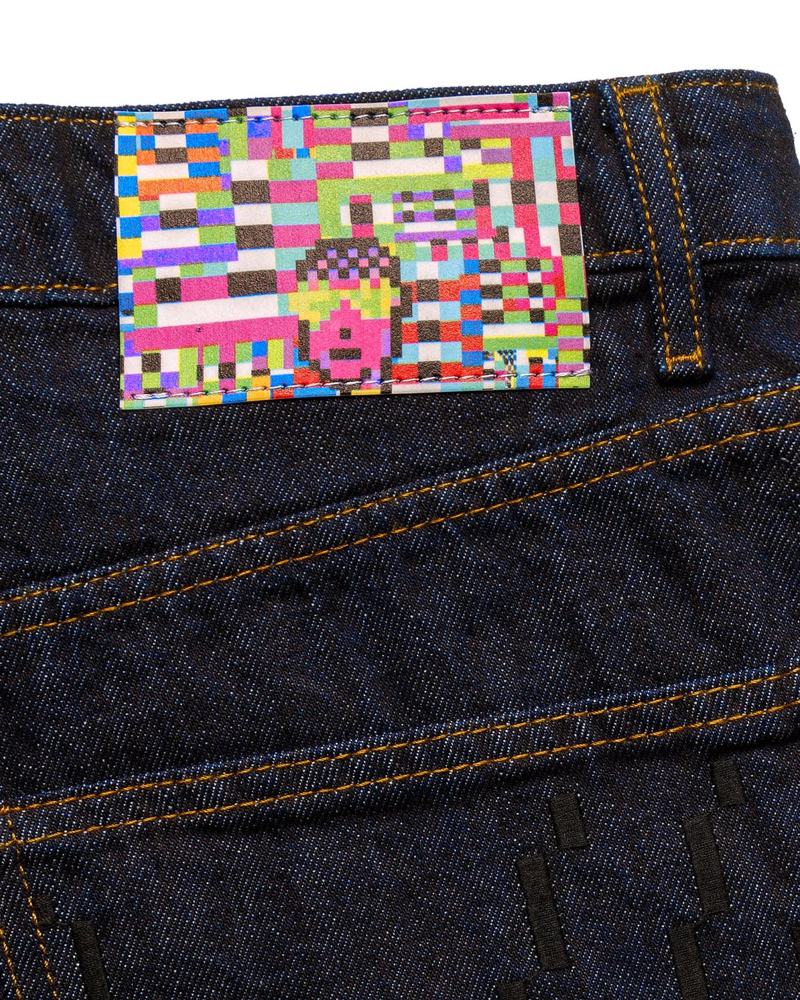 Side profile lifestyle view of a male model wearing the GLIX "The Maze" masculine fit jeans, highlighting the straight-leg silhouette and the tonal blue pixelated maze graphic printed on the lower leg of the dark wash denim.