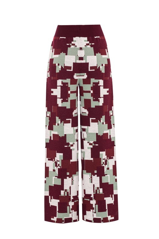 Rear flat lay view of the GLIX "Cherry Moo" knit pants on a white background, featuring an all-over jacquard knit pixelated glitch pattern in burgundy, sage green, and white, with a wide solid burgundy ribbed elasticated waistband, no back pockets, and a cropped wide-leg silhouette.
