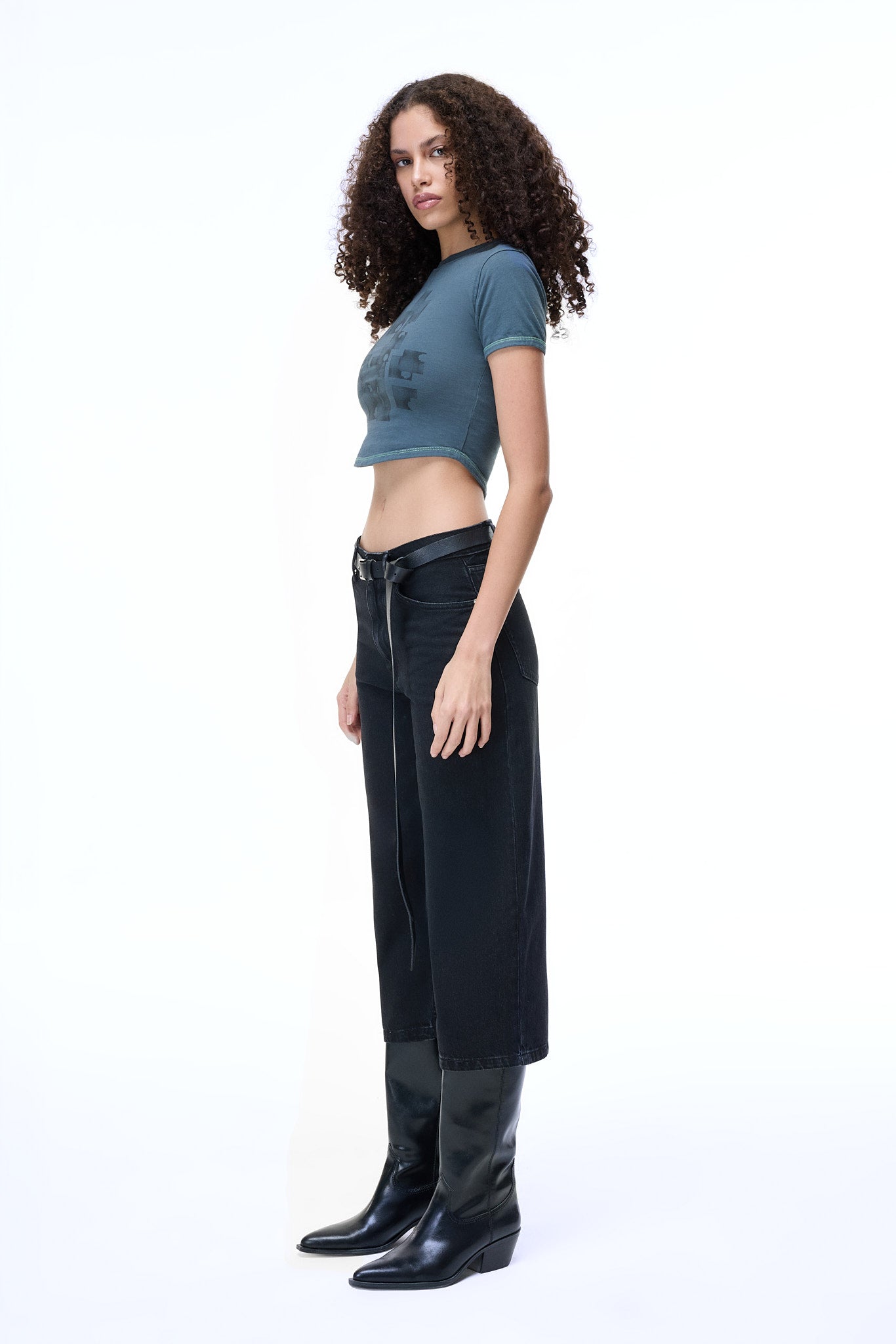 Side profile of a model wearing the GLIX MOLD PROBLEM dark grey crop top baby tee with a slim feminine fit and architectural curved hem.
