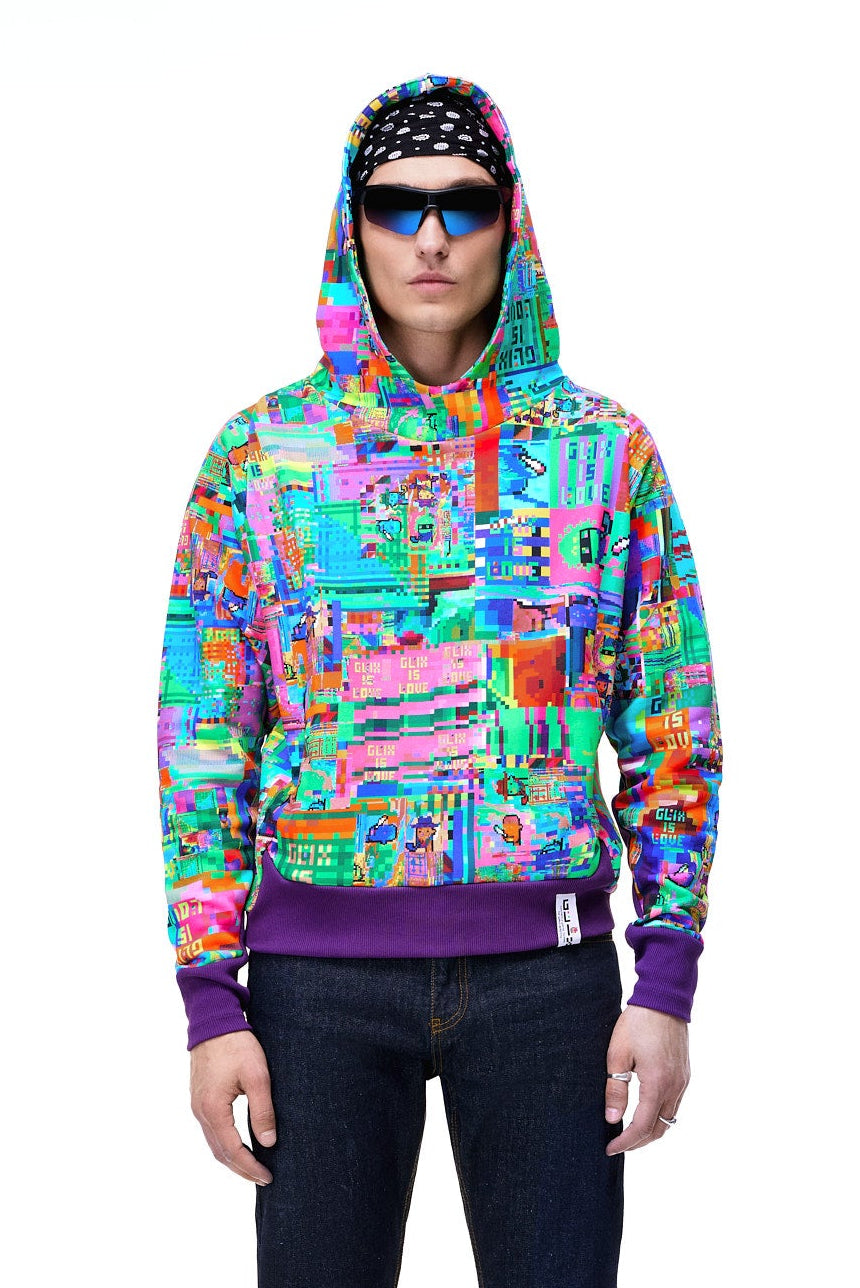 Front view of a male model wearing the vibrant multicolor GLIX "Glix Is Love" oversized hoodie with a purple ribbed hem, featuring a maximalist all-over digital glitch print, styled with blue jeans, futuristic sunglasses, and a black and white bandana.