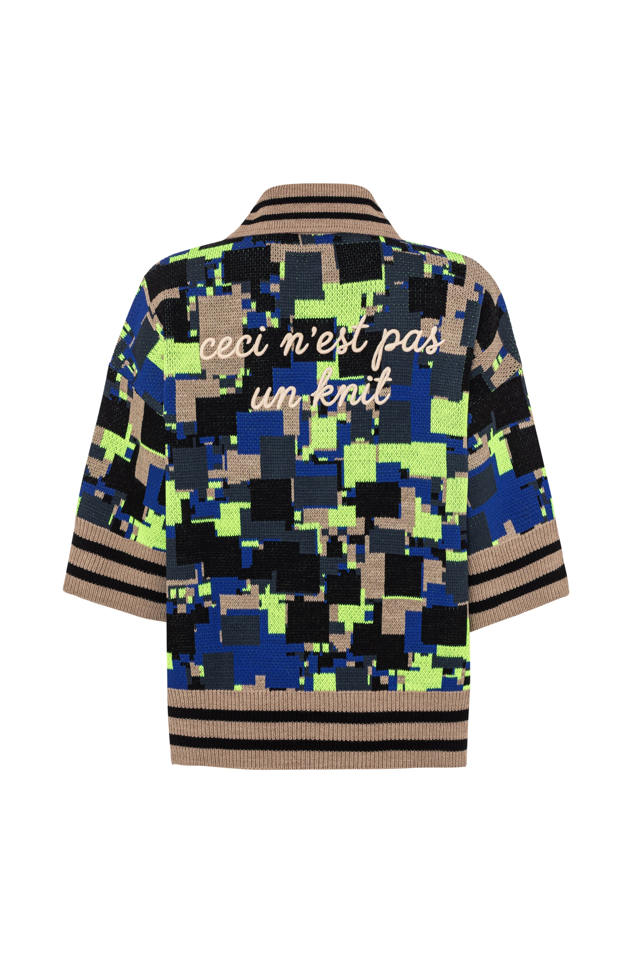 Rear flat lay view of the GLIX "No Knit" oversized short-sleeve jacquard knit polo sweater on a white background, featuring an all-over pixelated glitch pattern in cobalt blue, neon yellow-green, black, and camel, with the embroidered text "ceci n'est pas un knit" in cream script across the upper back, and camel-and-black striped ribbed hem and cuffs.