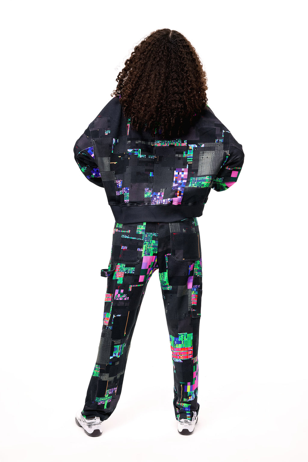 Back view of the GLIX SCREEN ERROR black hoodie and matching sweatpants, highlighting the expansive digital distortion print and architectural silhouette.