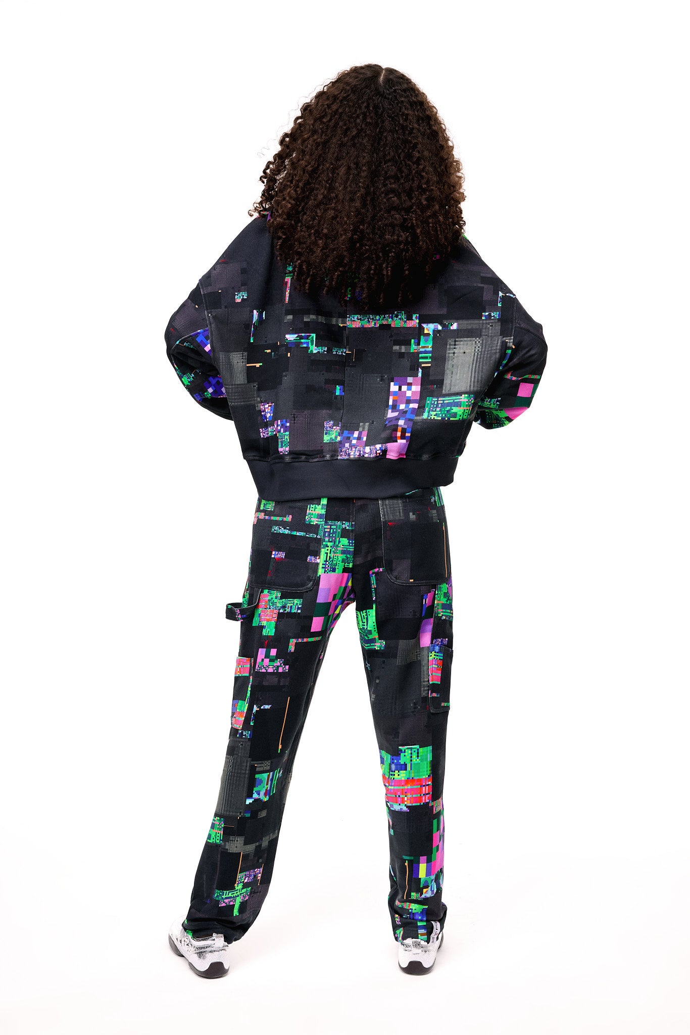 Back view of the GLIX SCREEN ERROR black hoodie and matching sweatpants, highlighting the expansive digital distortion print and architectural silhouette.