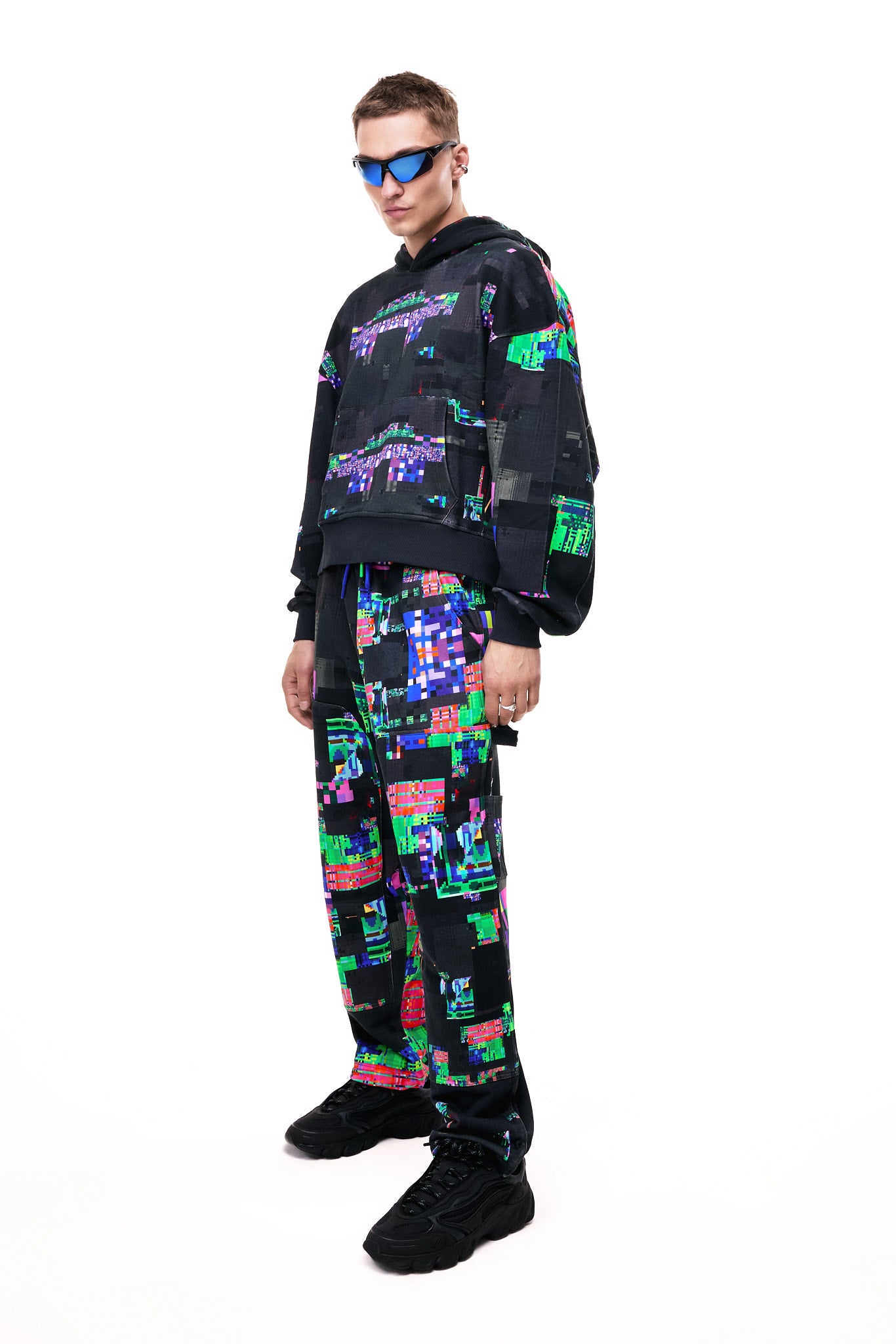 Front view of a model wearing the GLIX SCREEN ERROR black hoodie, featuring a vibrant neon generative glitch art pattern and an oversized streetwear fit.
