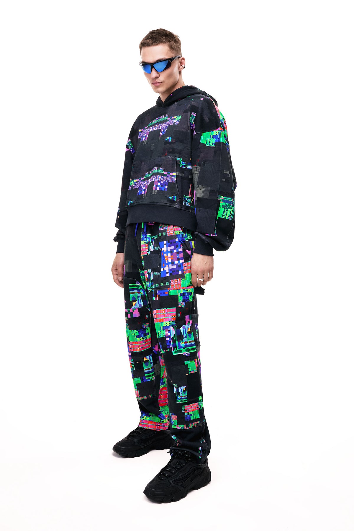 Front view of a model wearing the GLIX SCREEN ERROR black hoodie, featuring a vibrant neon generative glitch art pattern and an oversized streetwear fit.