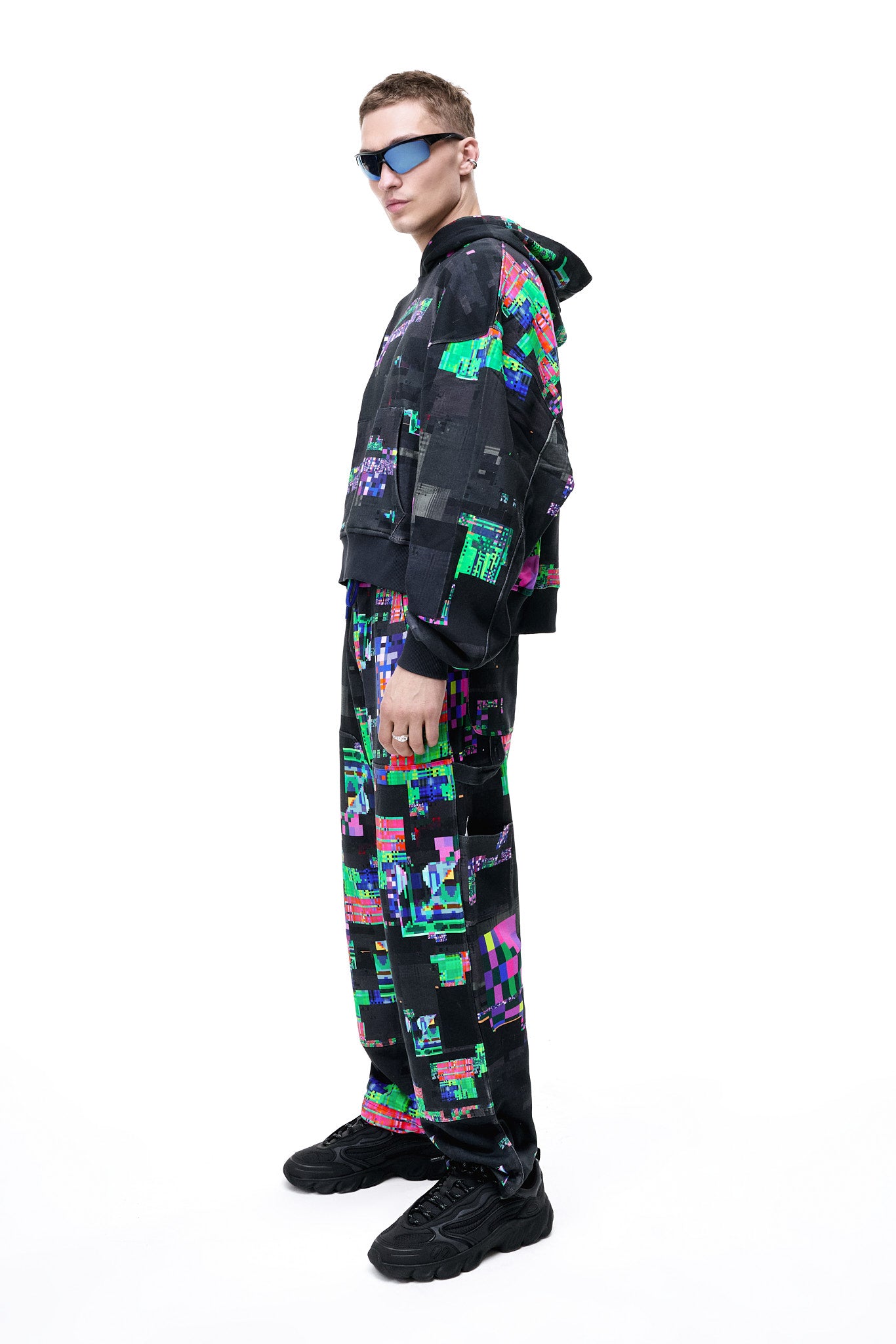 Side view of a model wearing the GLIX SCREEN ERROR black hoodie, featuring a vibrant neon generative glitch art pattern and an oversized streetwear fit.