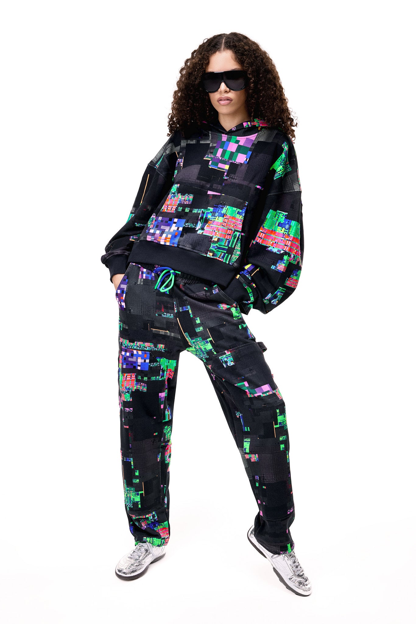 Front view of a model wearing the GLIX SCREEN ERROR black hoodie, featuring a vibrant neon generative glitch art pattern and an oversized streetwear fit.