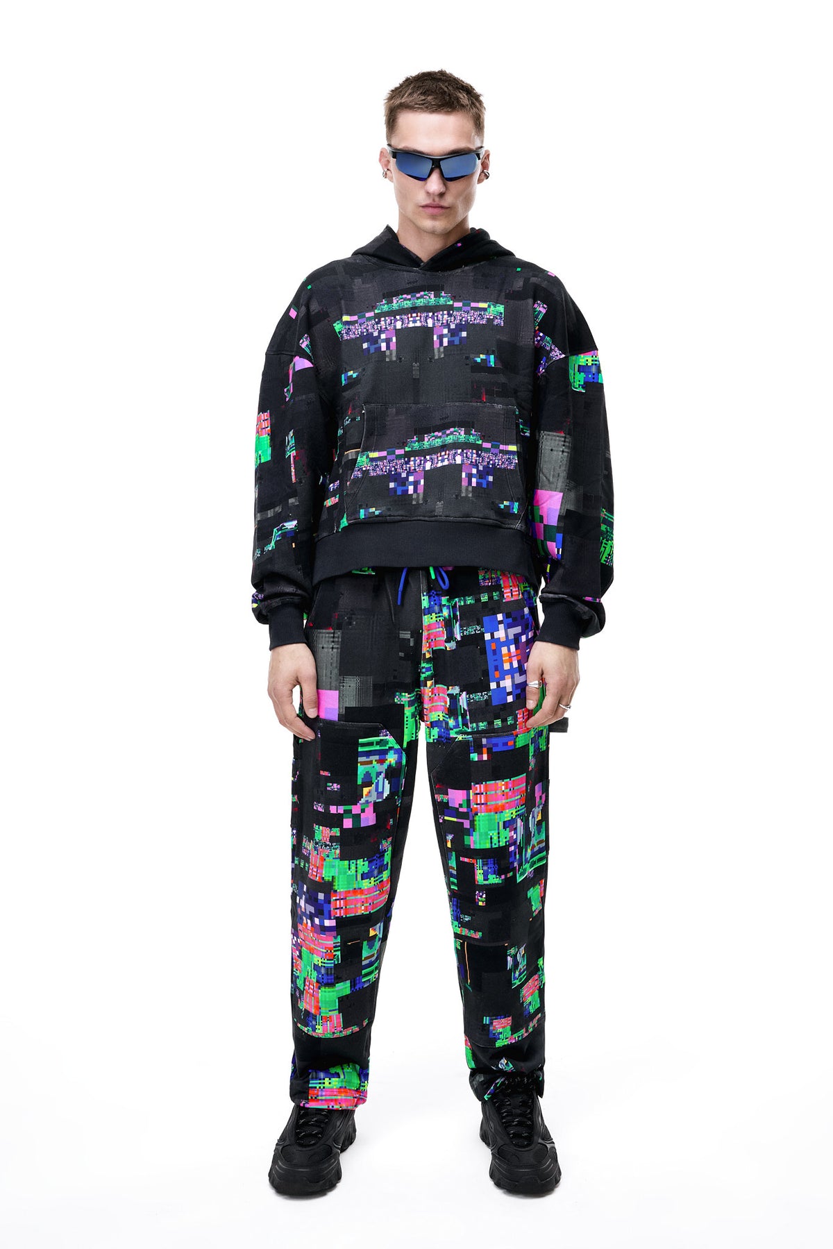 Front view of a model wearing the GLIX SCREEN ERROR black hoodie, featuring a vibrant neon generative glitch art pattern and an oversized streetwear fit.