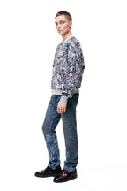 Side profile of a male model wearing the GLIX "Colors' Echo" oversized sweatshirt, highlighting the seamless continuation of the multicolor digital glitch print across the sleeves and the structured fit of the grey ribbed cuffs.