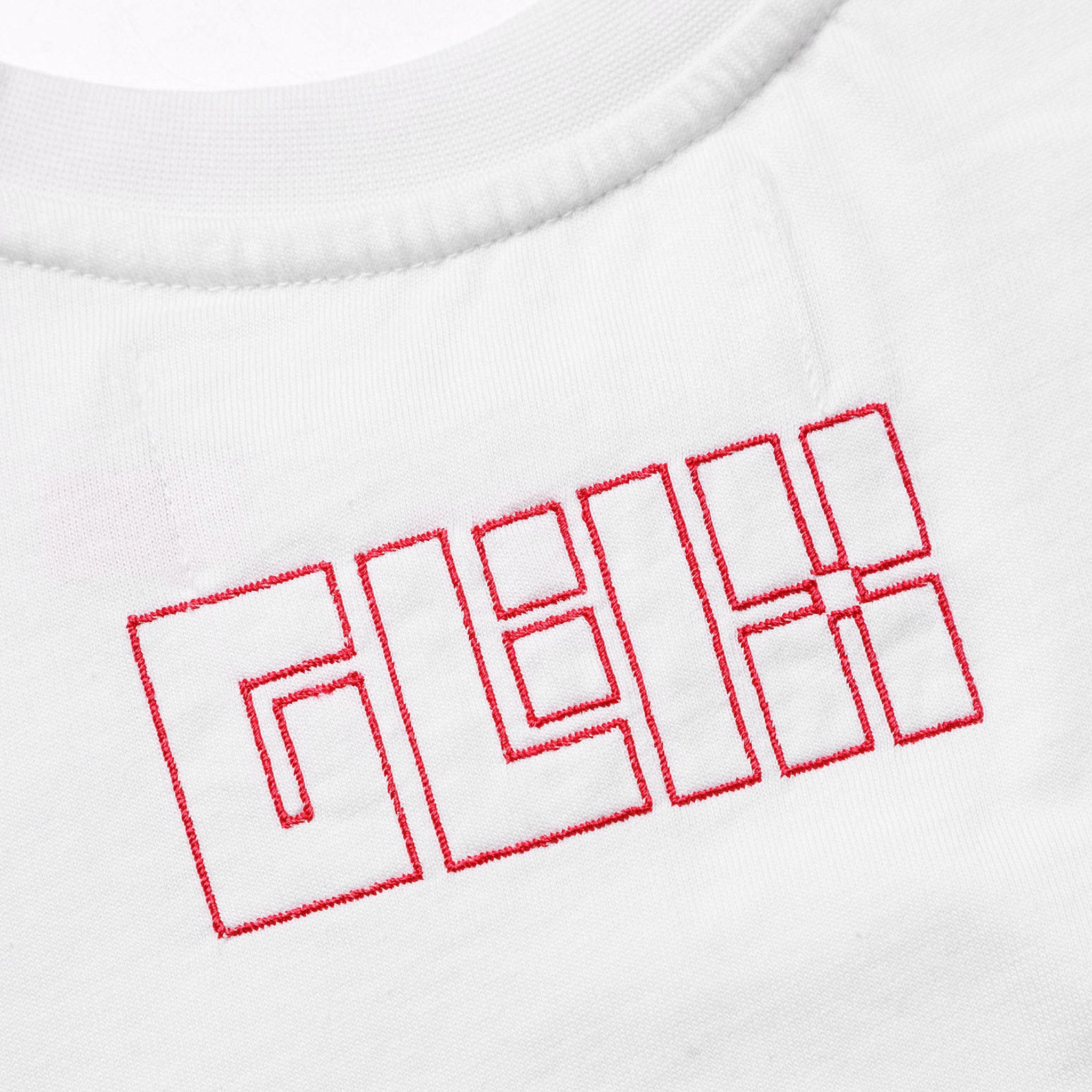 Close-up of the red embroidered GLIX block letter logo on the chest of a white crop top baby tee.